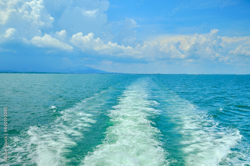 Fototapeta premium White bubbles and splashes of waves on the stern of the ferry that holiday traveled to the Sea of Thailand in a blue sky. The ship was moving fast in the view of the ocean and nobody on the deck.