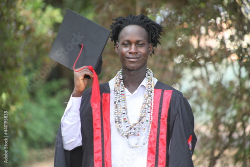 The African traditional man graduates on his graduation day and is looking straight into the camera with a wonderful smile with the African beads in his neck