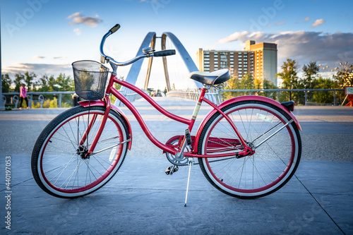 Calgary Alberta Canada, May 30, 2021: A vintage ladies cruiser bicycle parked on a downtown pathway in front of a pedestrian bridge in East Village Calgary. photo