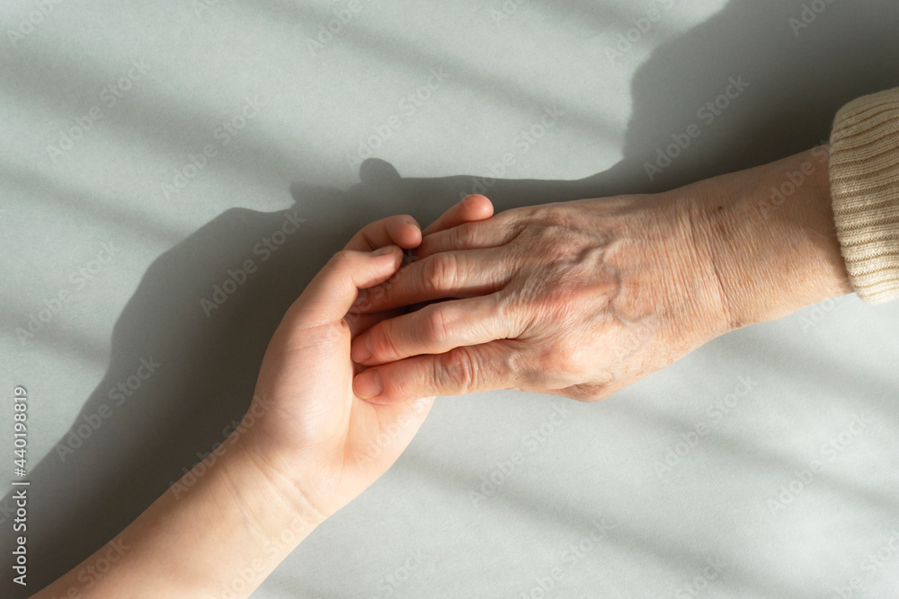 Grandmother's hand grabbing dear grandchild's hand under the light through the curtain. カーテン越しの光の下で愛しい孫の手をつかむ祖母の手 Grandmother's hand grabbing dear grandchild's hand under the light through the curtain. カーテン越しの光の下で愛しい孫の手をつかむ祖母の手