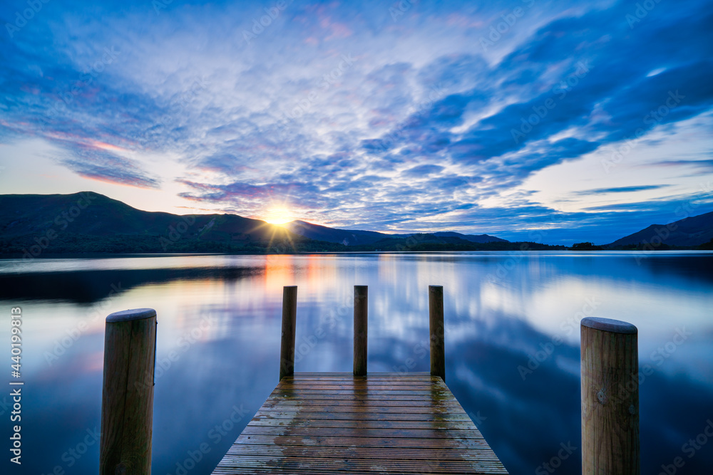 Vibrant sunset wooden jetty at Derwentwater Lake in the Lake District, UK.