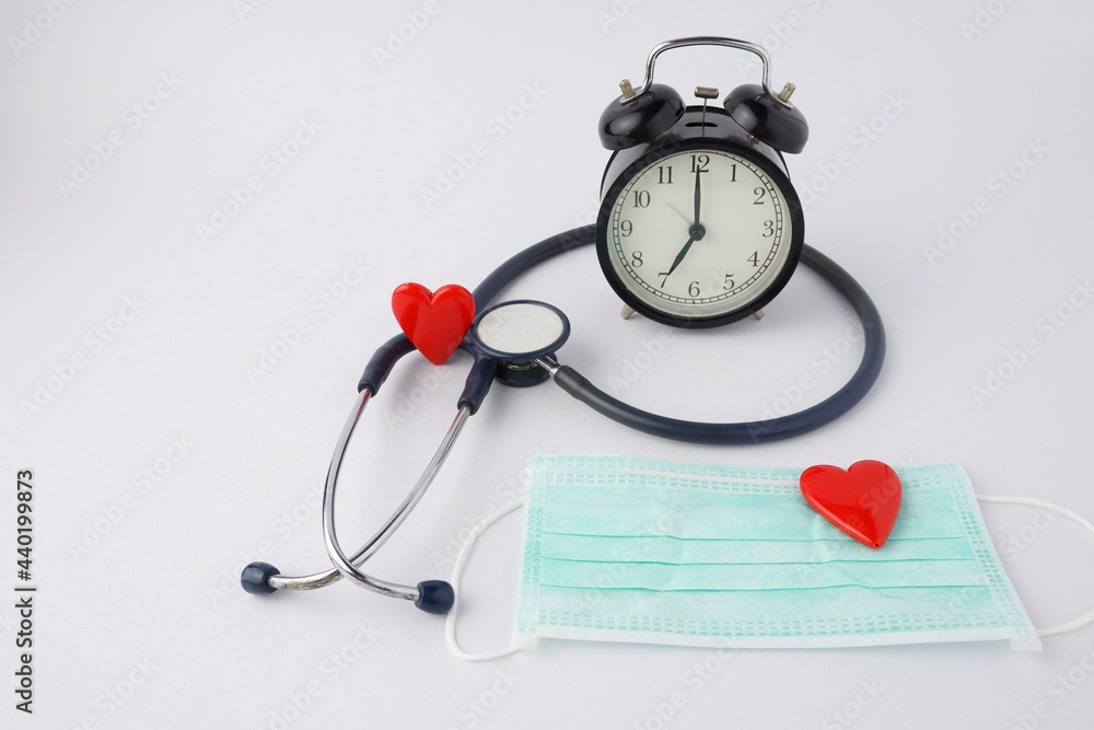 black alarm clock with red heart mask with medical stethoscope isolated on white background black alarm clock with red heart mask with medical stethoscope isolated on white background