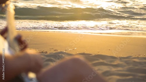 Man playing guitar by the sea at sunset