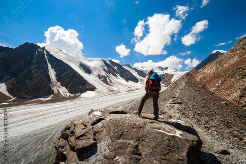 Photo of a tourist girl in the Altai Mountains. In the background is the Bolshoy Aktru Glacier, one of the oldest glaciers in the Altai Mountains.