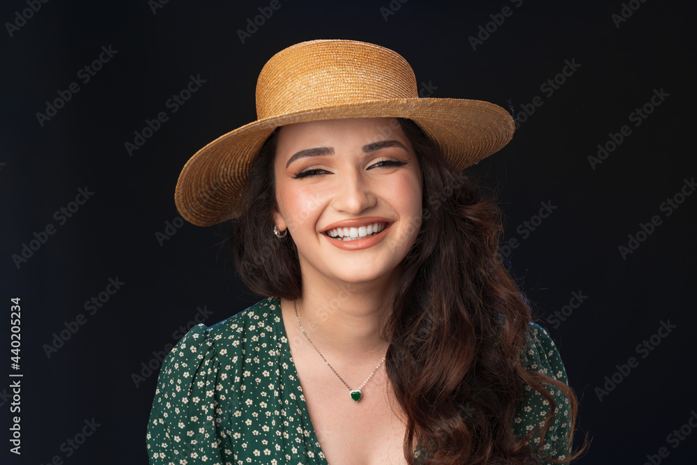 Beautiful young woman with straw hat posing against black background Beautiful young woman with straw hat posing against black background