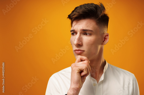 Portrait of thoughtful young man who looks away touching his chin