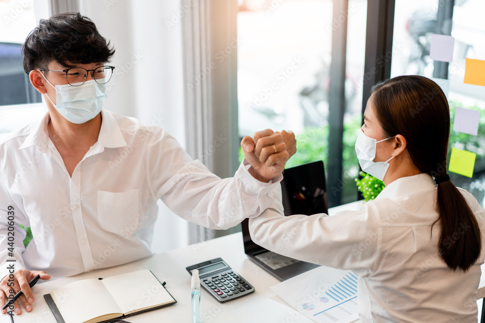 two business partners wearing protective mask touching elbows together agreed to work on the new project two business partners wearing protective mask touching elbows together agreed to work on the new project