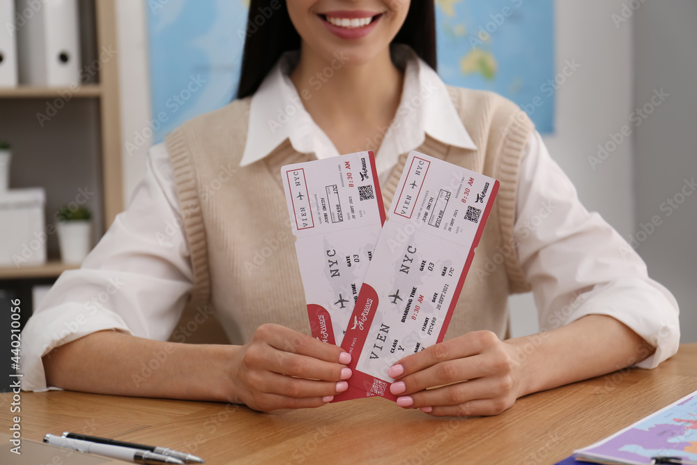 Travel agent with tickets at table in office, closeup