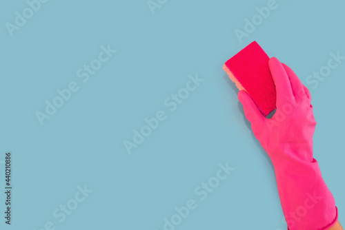 hand in a pink glove holds a washcloth isolated on a blue background. Copy space.