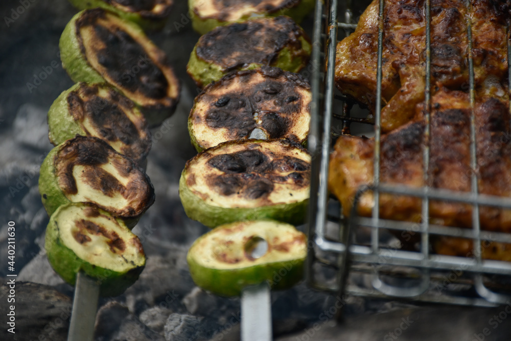 Delicious grilled zucchini skewers in the fire smoke and meat with golden crust. Delicious grilled zucchini skewers in the fire smoke and meat with golden crust.