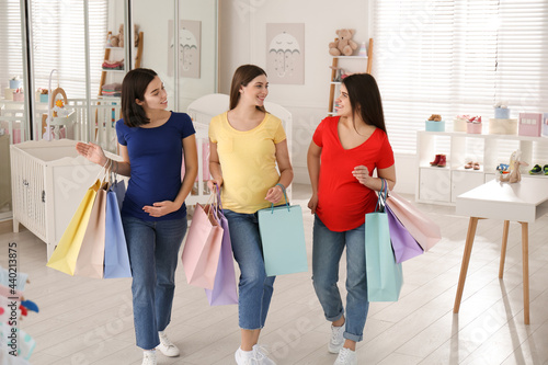 Happy pregnant women with shopping bags in store