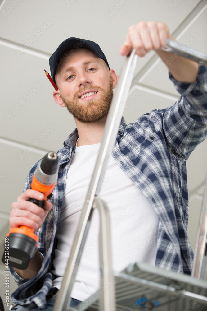 handsome young builder installing light on the ceiling handsome young builder installing light on the ceiling
