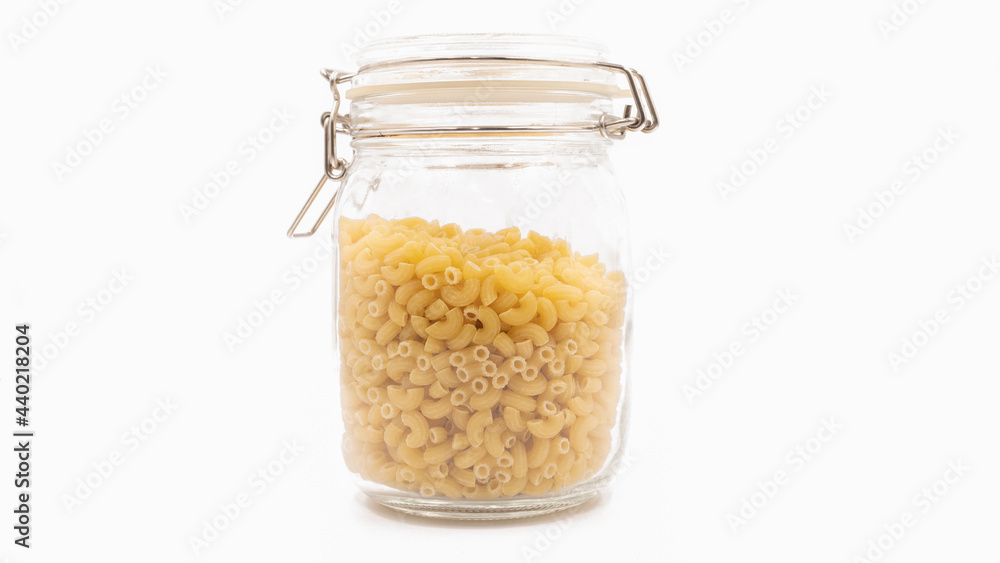 Isolated, The uncooked macaroni in the glass bottle on the white background Isolated, The uncooked macaroni in the glass bottle on the white background