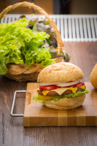 Home made hamburger with beef, onion, tomato, lettuce and cheese. Fresh burger closeup on wooden rustic table with potato fries, beer and chips. Cheeseburger. photo