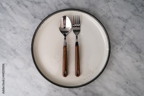 spoon and fork on empty plate on marble table