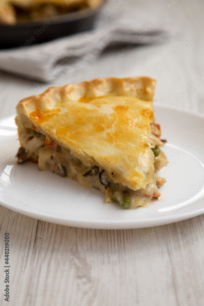 A Piece of Chicken Pot Pie on a white plate on a white wooden background, side view. A Piece of Chicken Pot Pie on a white plate on a white wooden background, side view.