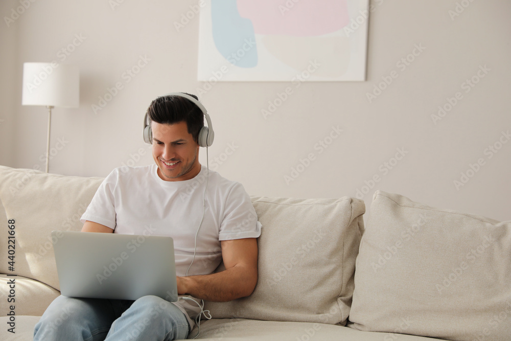 Man with laptop and headphones sitting on sofa at home Man with laptop and headphones sitting on sofa at home