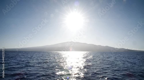 Sun reflecting on the ocean with siland on the back way to Molokini Crater, Hawaii. Mid angle, static movement, slow motion, HD. photo