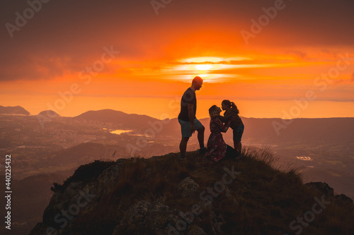 Parents with their son on top of a mountain at sunset  kisses and family love. Adventure lifestyle A summer afternoon in the mountains of the Basque country