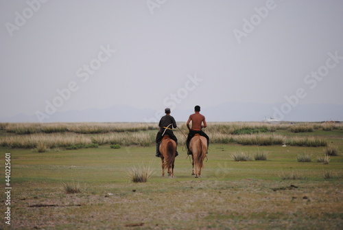 馬に乗って草原を駆け抜けるモンゴル人