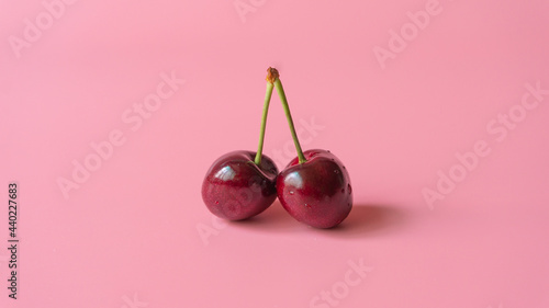 Two heart shaped cherry berries on pink background