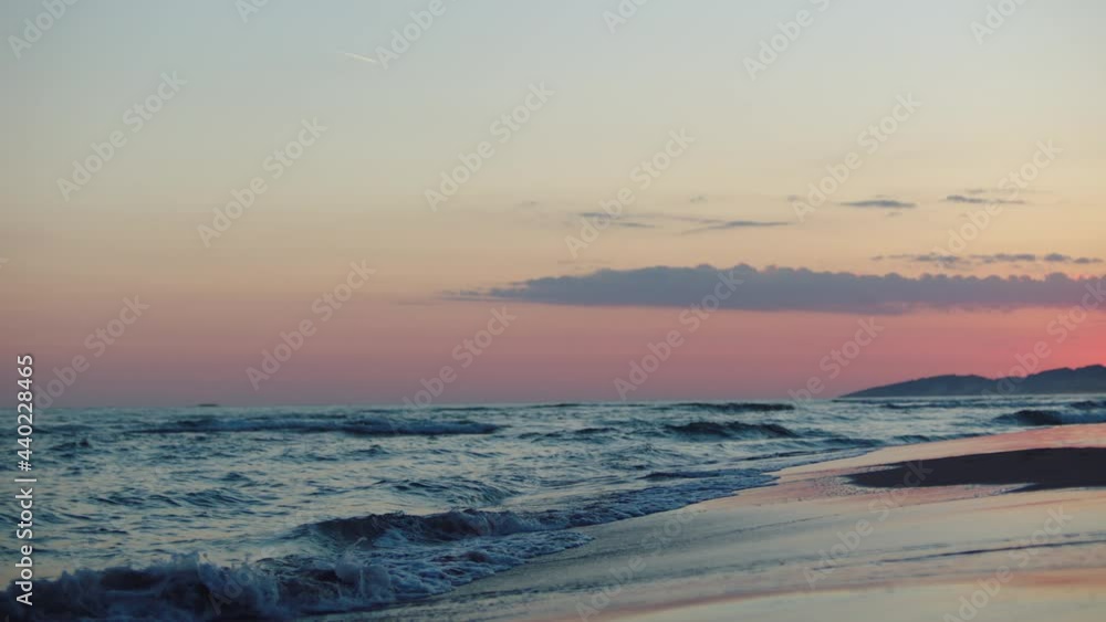 Sea waves washing beach after sunset. Water and wet sand reflecting pink twilight sky. Summer evening at seaside. Sea waves washing beach after sunset. Water and wet sand reflecting pink twilight sky. Summer evening at seaside.