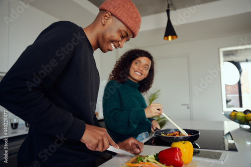 Fotografie Young mixed race couple cooking food in the kitchen at home