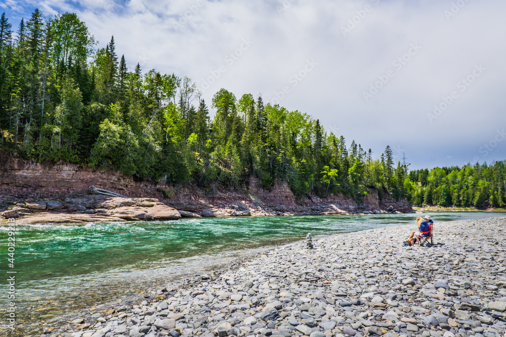 Tourists picnicking on the rocky beach of the Malin, a meander of the Bonaventure river, famous for its crystal blue waters  in Quebec (Canada)