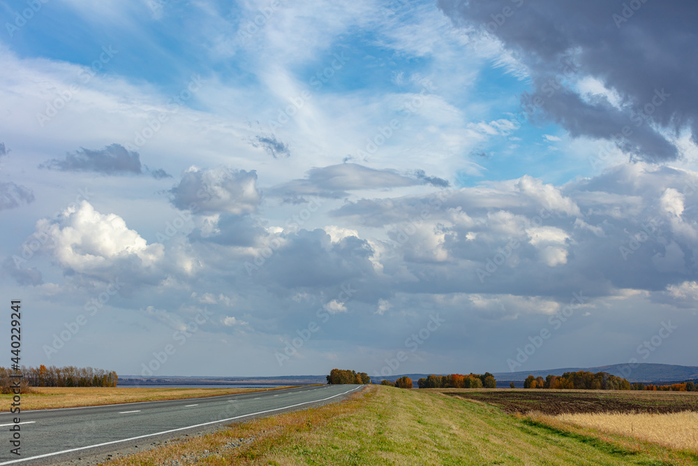 panorama of fantastic sky with old asphalt highway. country road leads through the fields. Countryside road in siberia. copy space