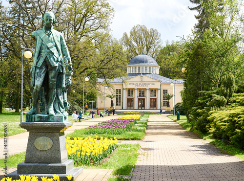 Spa promenade with flower bed in front of Glauber mineral springs building                              