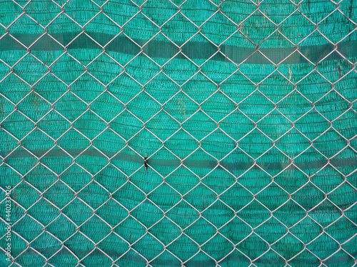 Background of steel mesh with green plastic sheet.