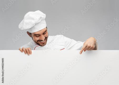 cooking, culinary and people concept - happy smiling male chef in toque with big white board over grey background