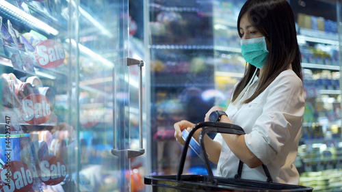 Woman in protective medical mask is choosing to buy items at supermarket.