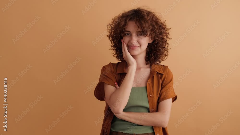 A charming woman is sending an air kiss standing isolated over a beige wall in the studio A charming woman is sending an air kiss standing isolated over a beige wall in the studio