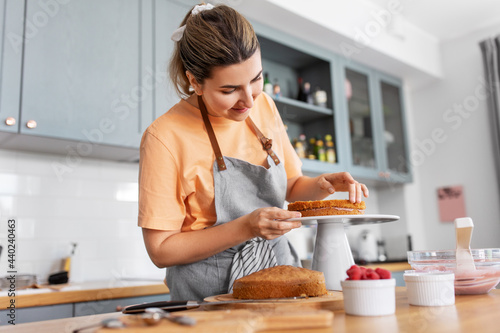 Obraz na plátne culinary, baking and cooking food concept - happy smiling young woman making lay