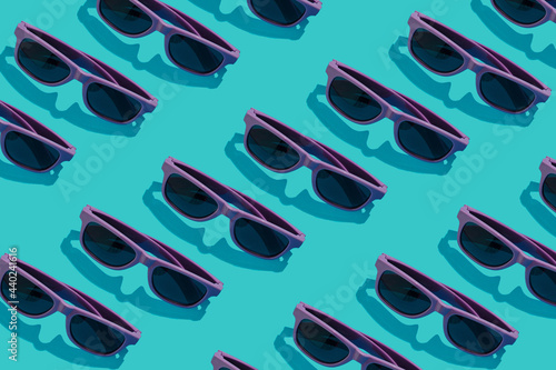 Purple sunglasses lay down on a pastel blue background. Flat lay pattern composition, summer chill out concept