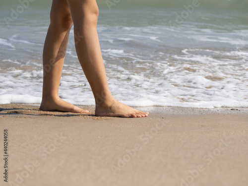 crop photo of legs walking on the white sand beach 