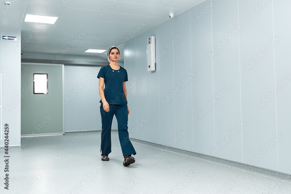 Woman doctor walking down the corridor of the hospital tired surgeon after surgery Woman doctor walking down the corridor of the hospital tired surgeon after surgery