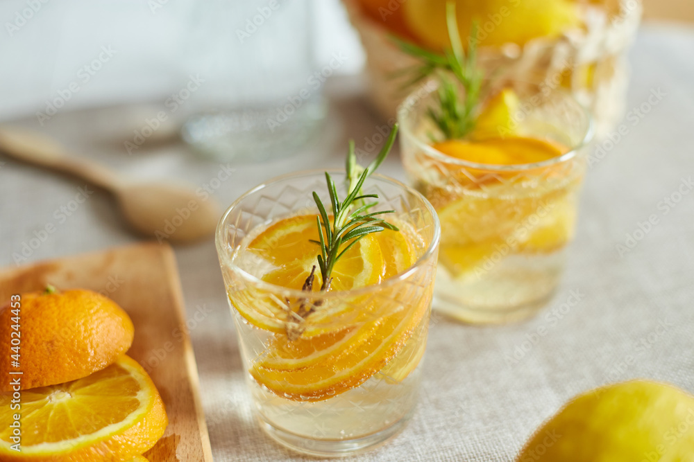 Fototapeta premium Citrus and rosemary fresh lemonade in glass on a white table at home