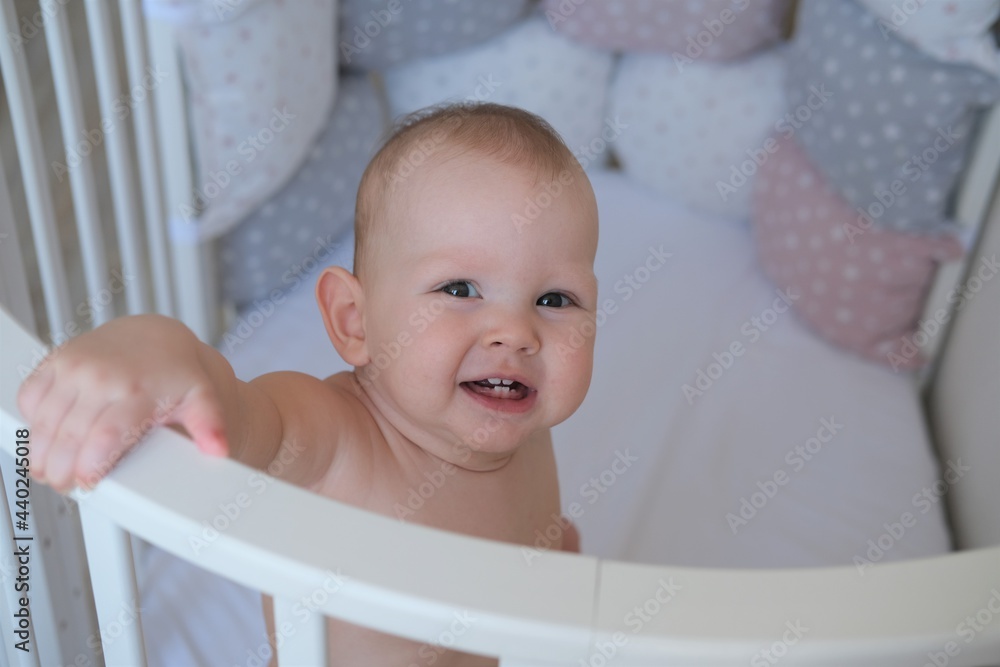 Close-up of a small child standing in a crib. The toddler does not want to sleep in the bed. Close-up of a small child standing in a crib. The toddler does not want to sleep in the bed.