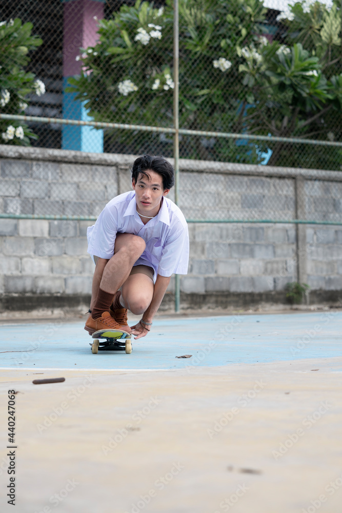 Teen Asian Skater boy in student uniform skating in the local skate park. Teen Asian Skater boy in student uniform skating in the local skate park.