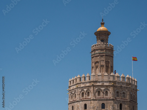 View of Torre del Oro (Tower of Gold) with spanish flag and blue sky and copy space