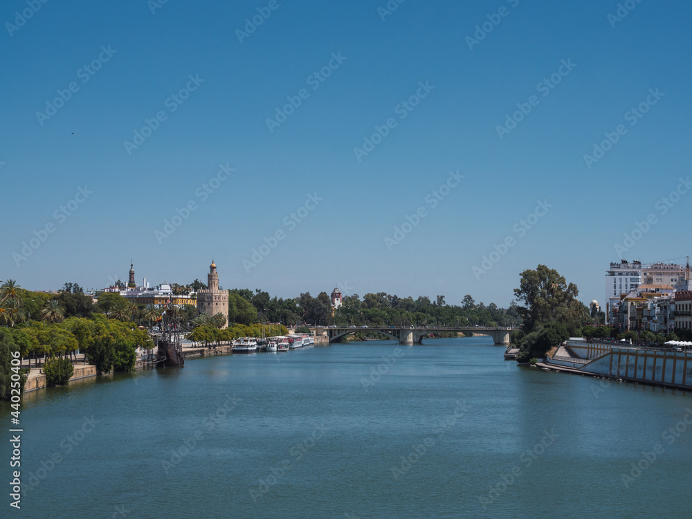 View of the city of Seville from the Guadalquivir river with the Torre del Oro (Tower of gold) and the north tower of the Plaza España (Spain Square) in the background