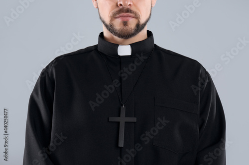 Priest wearing cassock with clerical collar on grey background, closeup