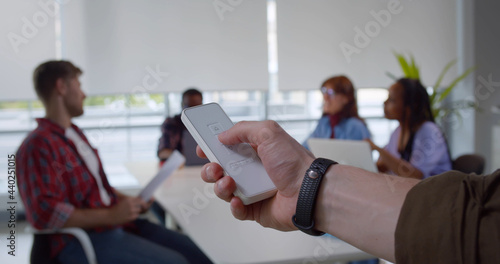 Close up of man hand holds remote control close window blinds in office