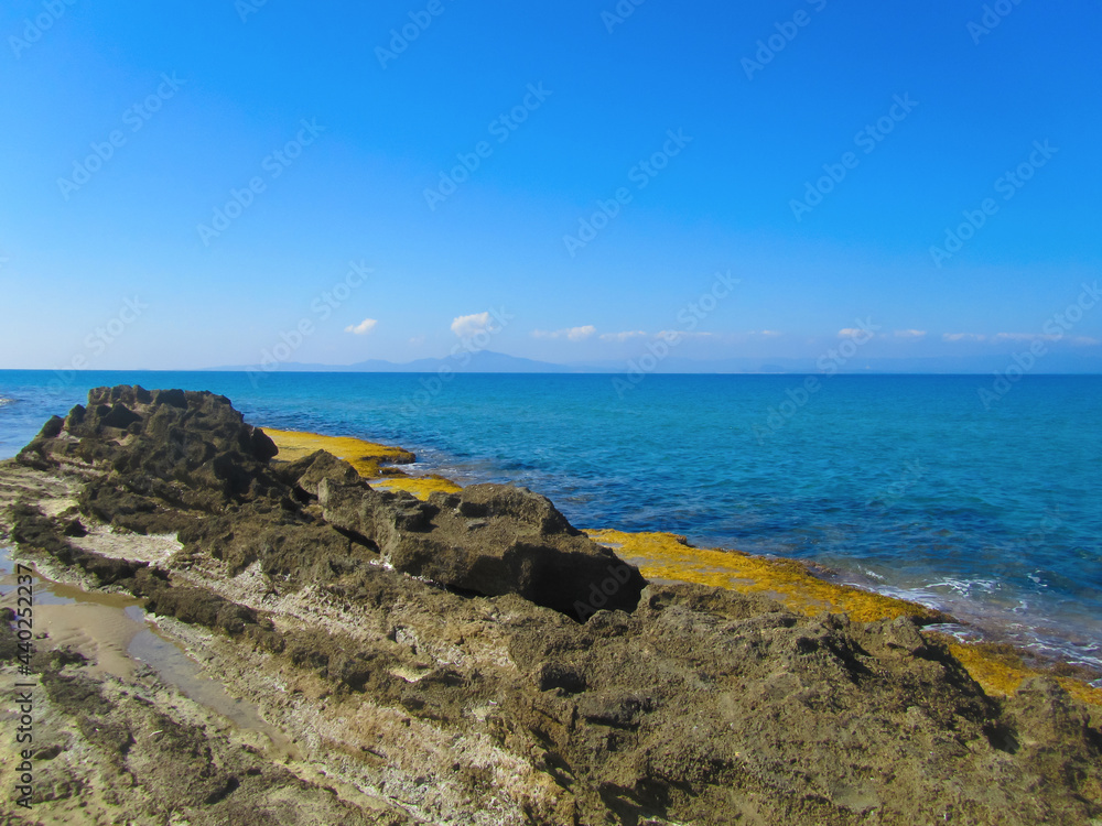 Rocky shore of the Ionian Sea against the background of azure sea water