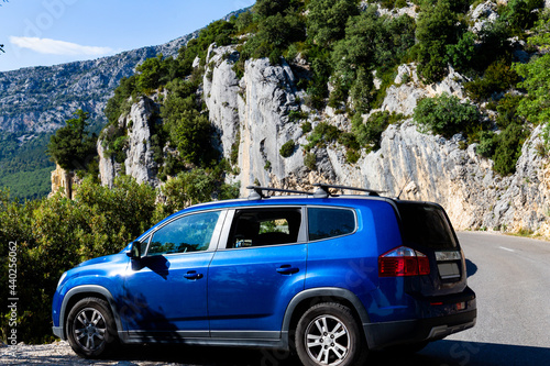 Blue hatchback small family car is parked on mountain road surrounded by rocks in Verdon Gorge national park in French Alps. © Anna