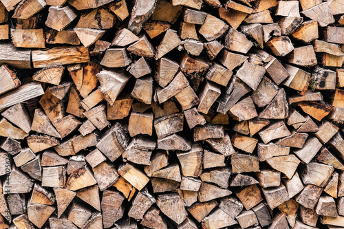 Background of stacked chopped wood logs. Harvesting firewood for the winter. A stack of firewood. Wooden textured background.