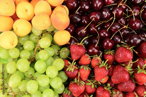 Fototapeta Naklejka Na Ścianę i Meble -  Fruits laid out on a horizontal surface. Apricots, grapes, strawberries and cherries