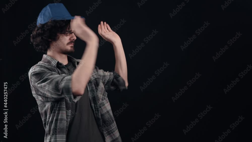 The boy with the blue, curly and handsome cap tries to cover his nose when he smells bad and tries to get rid of it with his hands. Isolated on black background. The concept of life. People's emotions The boy with the blue, curly and handsome cap tries to cover his nose when he smells bad and tries to get rid of it with his hands. Isolated on black background. The concept of life. People's emotions